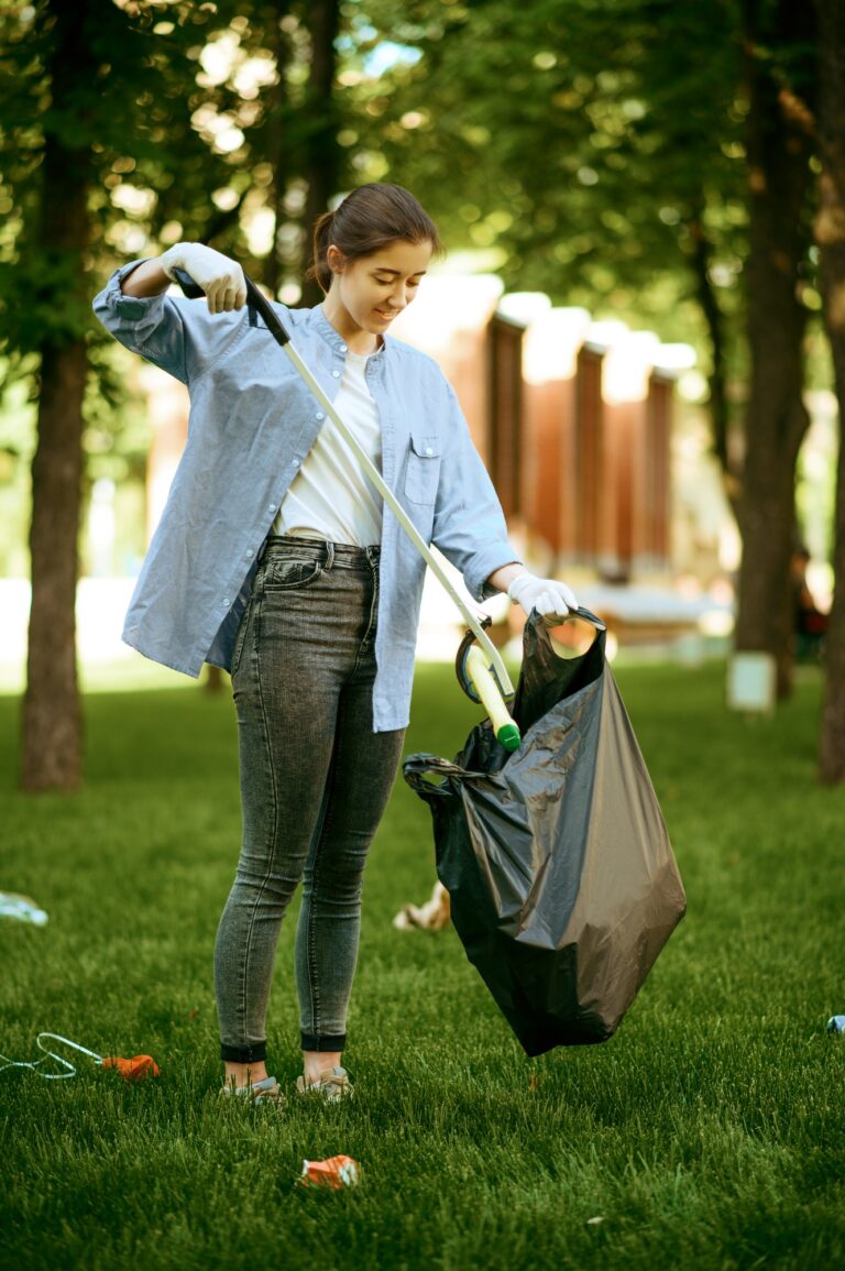 Young woman collects garbage in plastic bag